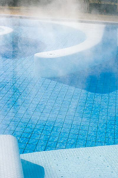Thermalbecken mit dampfender Wasseroberfläche über Fliesenmuster