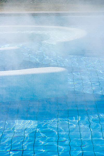 Innenpool mit blau-weißen Fliesen und Dampfwolken