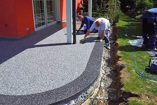 Handwerker bei der Verarbeitung eines grauen Steinteppichs